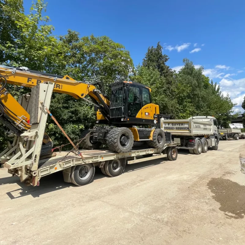 Transport: Gelber Bagger auf Tieflader. Baugerät.